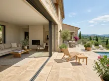Maison contemporaine ouverte sur une terrasse avec continuité visuelle entre intérieur et extérieur, carrelage coordonné effet pierre